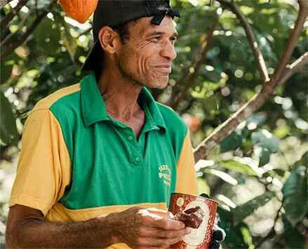 Um agricultor de cacau, desfrutando do fruto de seu trabalho: um chocolate Haoma, símbolo de dedicação à qualidade e à sustentabilidade.